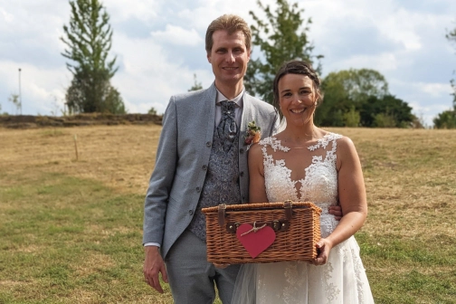 Ein Ehepaar mit einer Geschenkbox auf einer Wiese.