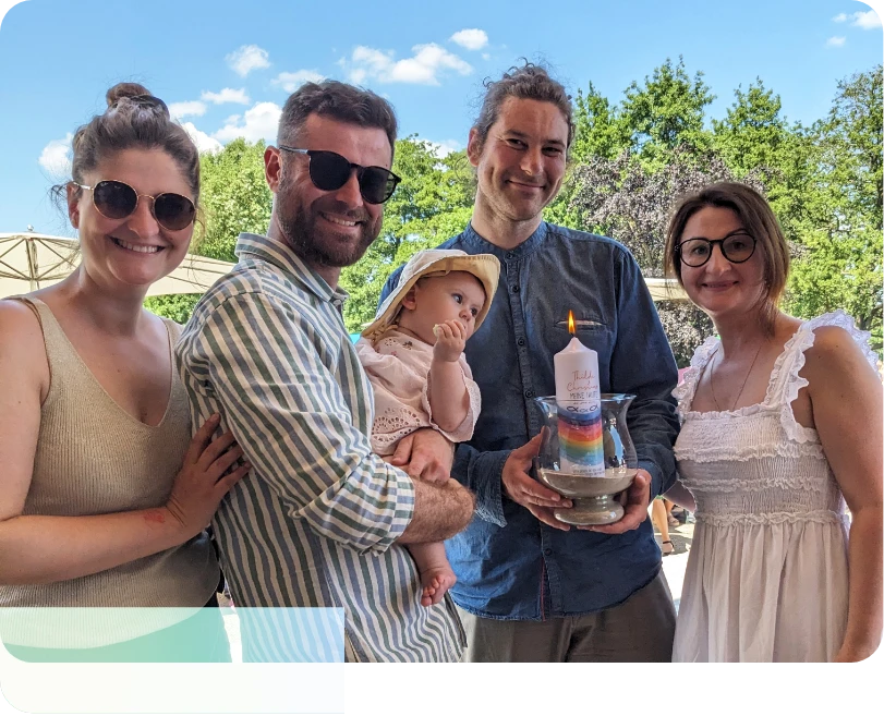 Eine Tauffamilie mit Taufkerze an einem schönen Tag.