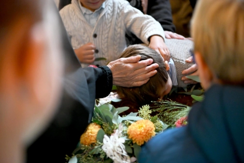 Ein Junge am Taufbecken während seiner Taufe.