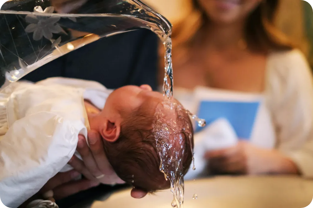 Ein Kind wird während einer Tauffeier mit Wasser übergossen.